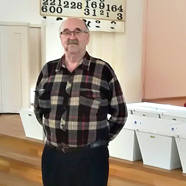 Mies seisoo kirkossa takanaan sotavainajien valkoisia pieniä arkkuja.